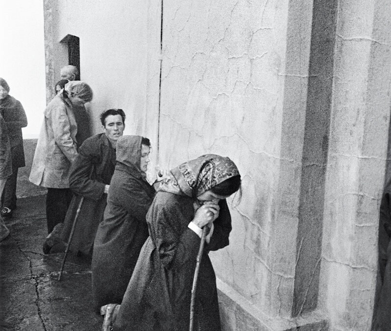 A line of people kneel at the side of a church praying.
