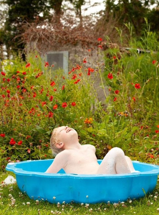 Child having fun in a small blue plastic swimming pool